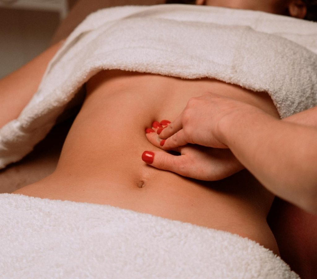 A soothing massage on a womans abdomen with painted nails, creating a serene spa atmosphere.